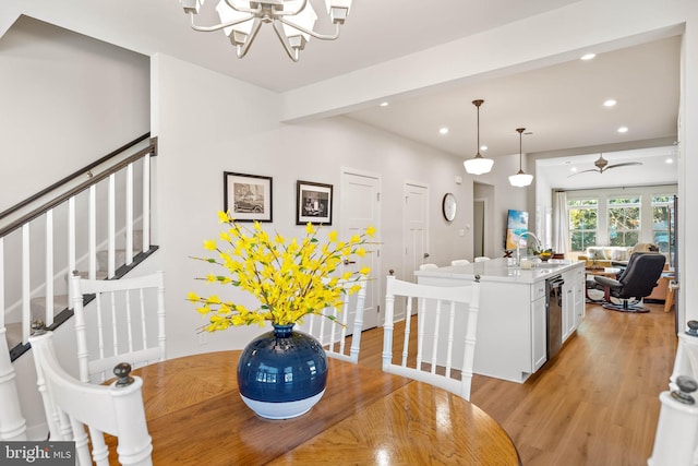 dining space with beam ceiling, sink, light hardwood / wood-style floors, and ceiling fan with notable chandelier