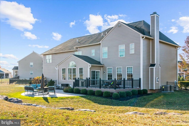 rear view of property featuring central AC unit, a patio area, and a lawn