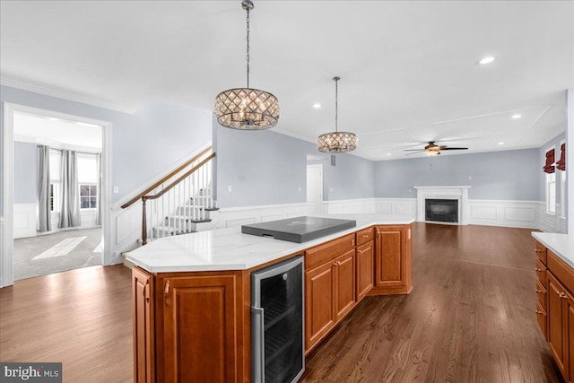 kitchen with a center island, hanging light fixtures, dark wood-type flooring, wine cooler, and ceiling fan with notable chandelier