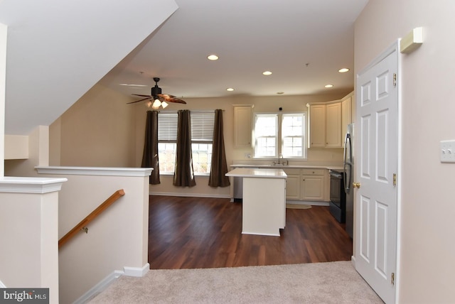 kitchen featuring cream cabinets, a kitchen breakfast bar, sink, dark colored carpet, and a center island