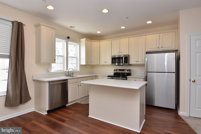 kitchen featuring appliances with stainless steel finishes, a center island, dark hardwood / wood-style floors, and sink