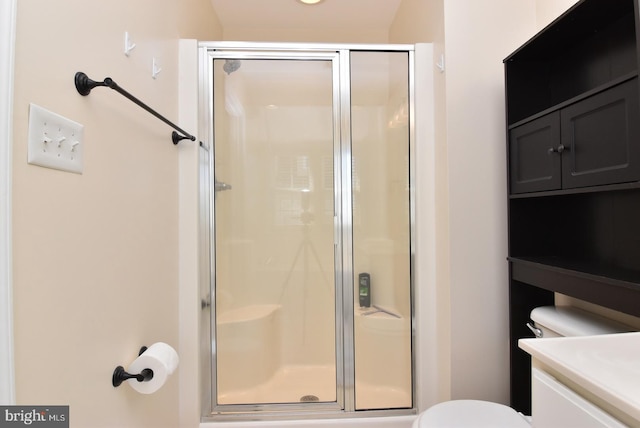 bathroom featuring a shower with door, vanity, and toilet