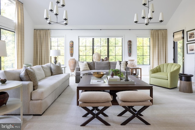 carpeted living room featuring high vaulted ceiling, an inviting chandelier, and a healthy amount of sunlight