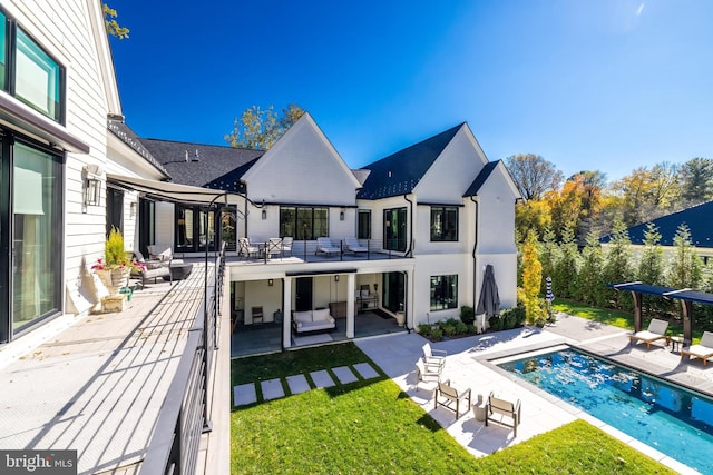 back of property featuring a lawn, a balcony, outdoor lounge area, and a patio