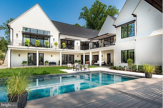 back of property featuring an outdoor living space, a balcony, and a patio area