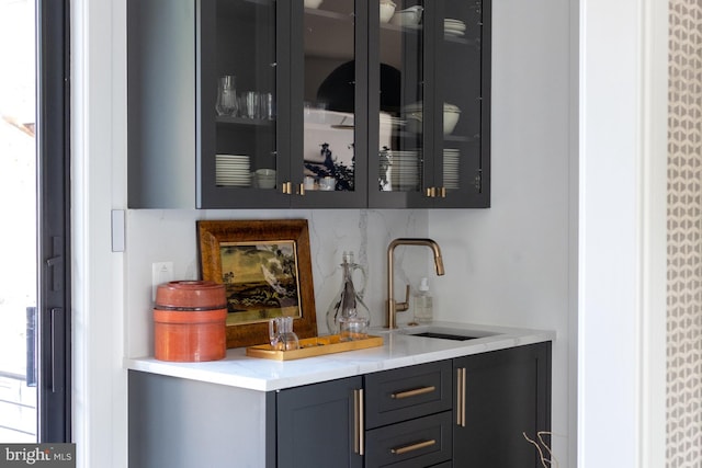 bar featuring gray cabinetry, backsplash, and sink