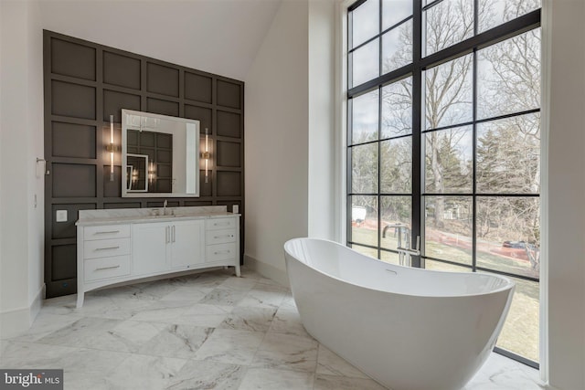 bathroom with high vaulted ceiling, a washtub, and vanity