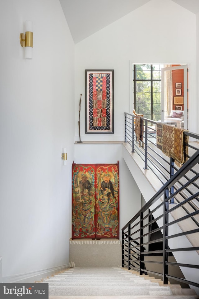 stairway featuring vaulted ceiling and carpet flooring