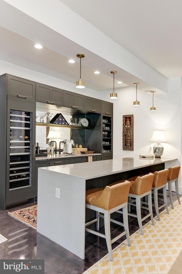 bar with beverage cooler, sink, decorative light fixtures, and gray cabinetry