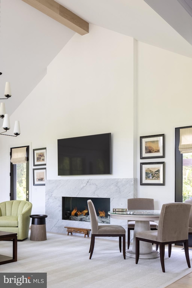 living room featuring high vaulted ceiling, hardwood / wood-style floors, a high end fireplace, and beam ceiling