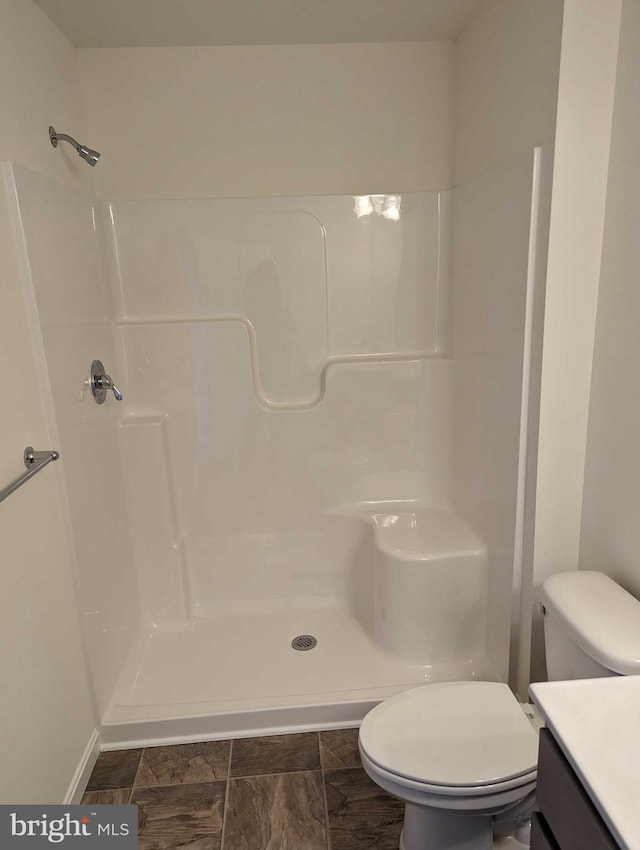 bathroom with walk in shower, vanity, and toilet