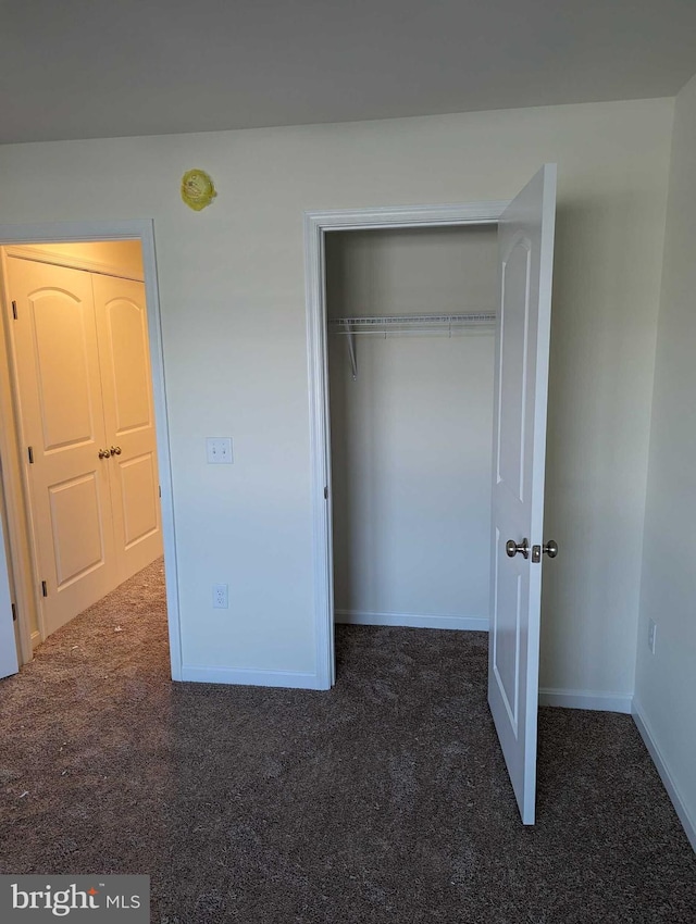 unfurnished bedroom featuring dark colored carpet and a closet