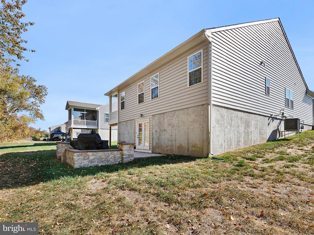 rear view of property featuring a yard, cooling unit, and a patio area