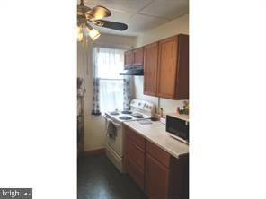 kitchen featuring white electric range oven, a drop ceiling, and range hood