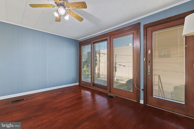 doorway to outside with dark wood-type flooring, crown molding, wooden walls, and ceiling fan