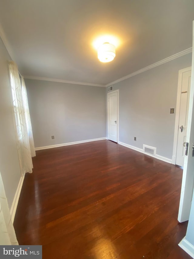 spare room with crown molding, dark wood finished floors, and baseboards