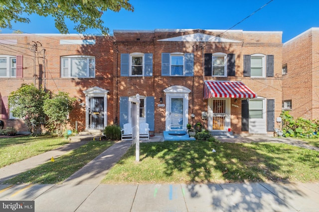 multi unit property with a front yard and brick siding