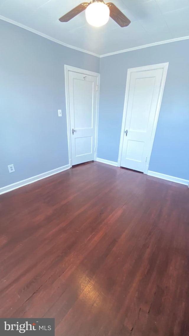 spare room with baseboards, ornamental molding, and dark wood-style flooring