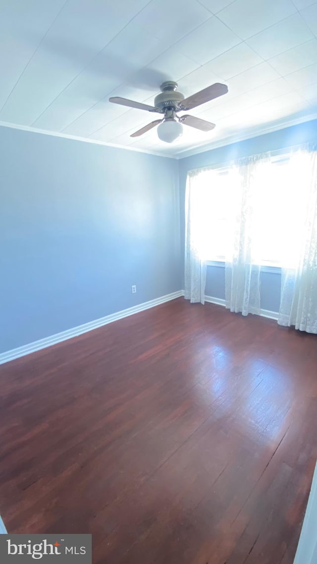 unfurnished room with a ceiling fan, ornamental molding, dark wood-style floors, and baseboards