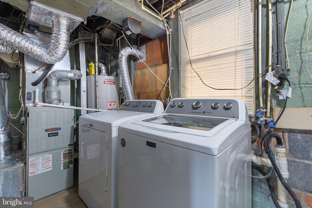 clothes washing area featuring water heater, heating unit, and washing machine and clothes dryer