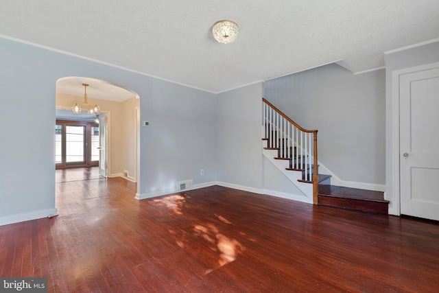 unfurnished living room with stairway, baseboards, ornamental molding, arched walkways, and wood finished floors
