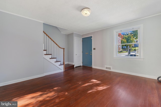 foyer with ornamental molding, visible vents, stairway, and wood finished floors