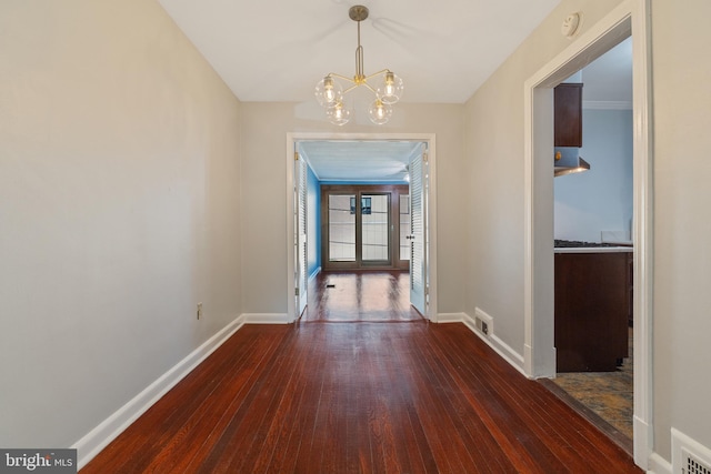 unfurnished dining area featuring ornamental molding, dark wood-type flooring, and a notable chandelier