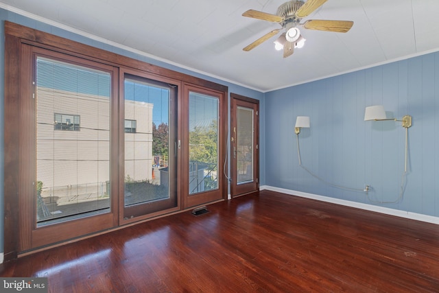 spare room with dark wood-type flooring, ceiling fan, and ornamental molding