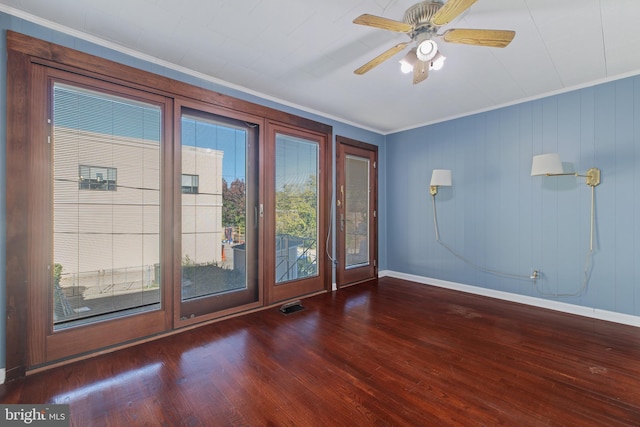 spare room featuring baseboards, visible vents, wood finished floors, and crown molding