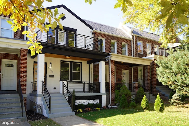 townhome / multi-family property featuring a front yard, covered porch, and a balcony