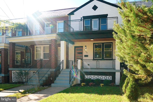 view of front of house with covered porch, a front yard, and a balcony