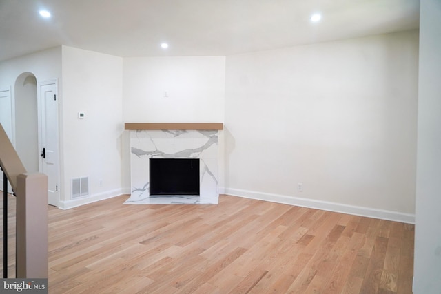 unfurnished living room with light wood-type flooring and a high end fireplace