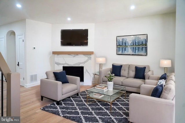 living room featuring a high end fireplace and hardwood / wood-style flooring