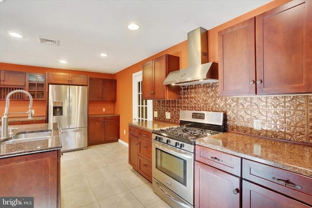 kitchen with sink, appliances with stainless steel finishes, wall chimney range hood, and dark stone counters