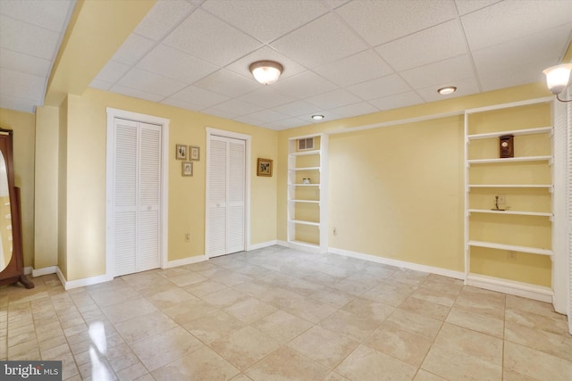 tiled spare room with built in shelves and a paneled ceiling