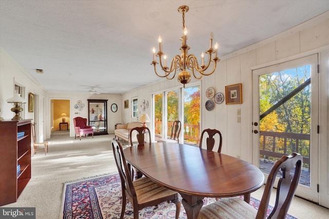 dining space featuring ceiling fan with notable chandelier, ornamental molding, plenty of natural light, and light colored carpet