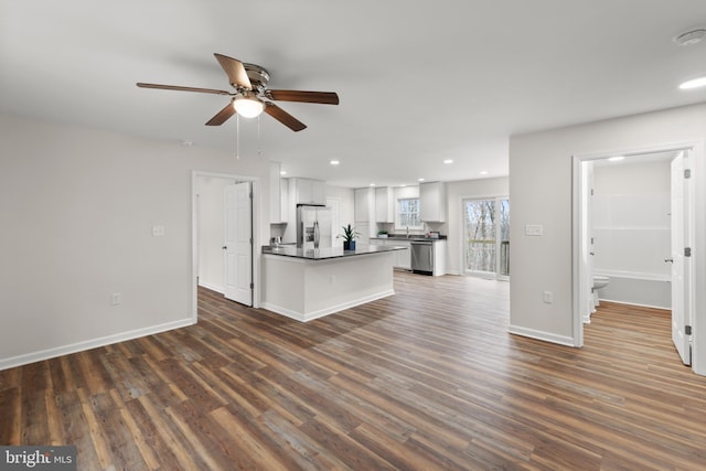 kitchen featuring dark wood-type flooring, ceiling fan, a kitchen island, white cabinetry, and stainless steel appliances