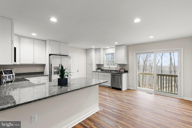 kitchen featuring white cabinets, stainless steel appliances, dark stone counters, and sink