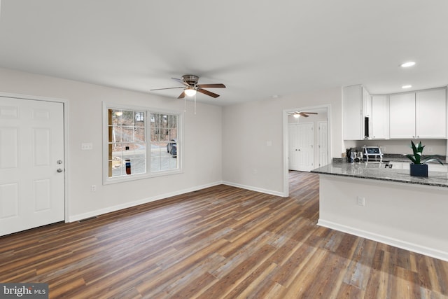 kitchen featuring dark stone countertops, ceiling fan, white cabinets, and dark wood-type flooring