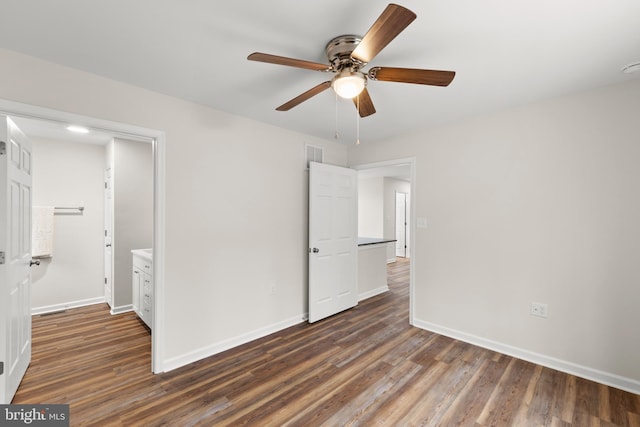 unfurnished bedroom with ceiling fan, dark wood-type flooring, and ensuite bathroom