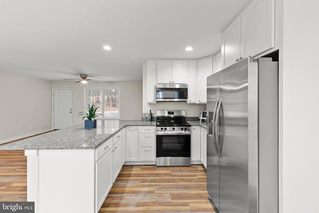 kitchen featuring kitchen peninsula, appliances with stainless steel finishes, white cabinetry, and ceiling fan