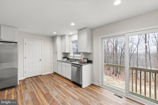 kitchen with white cabinets, appliances with stainless steel finishes, light hardwood / wood-style floors, and plenty of natural light