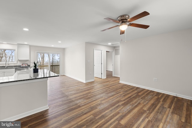 unfurnished living room with ceiling fan, dark wood-type flooring, and sink