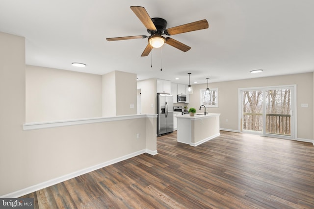 unfurnished living room featuring ceiling fan, dark wood-type flooring, and sink