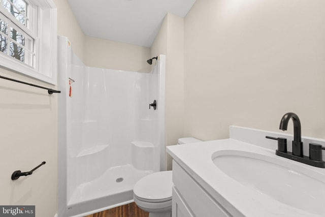 bathroom featuring a shower, hardwood / wood-style floors, vanity, and toilet