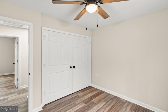 unfurnished bedroom with ceiling fan, dark hardwood / wood-style floors, and a closet