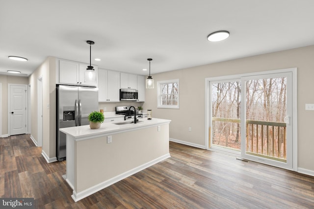 kitchen featuring sink, decorative light fixtures, a center island with sink, white cabinets, and appliances with stainless steel finishes