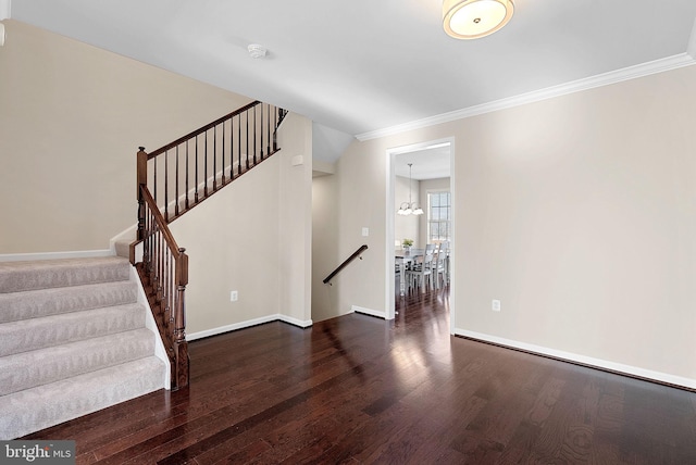 staircase with ornamental molding, a chandelier, and hardwood / wood-style floors