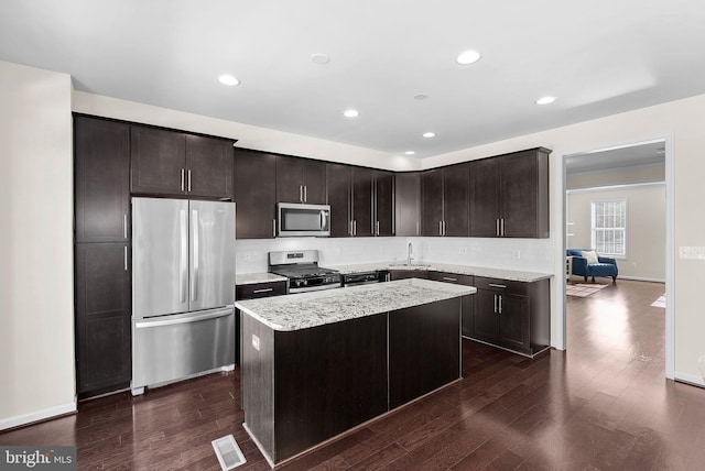 kitchen featuring stainless steel appliances, a kitchen island, sink, and dark brown cabinets