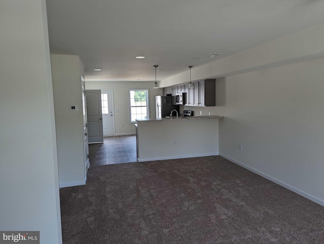 kitchen with kitchen peninsula, appliances with stainless steel finishes, dark colored carpet, and sink